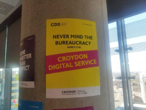 Pillar in office with poster: "Never mind the bureaucracy, here's the Croydon Digital Service"