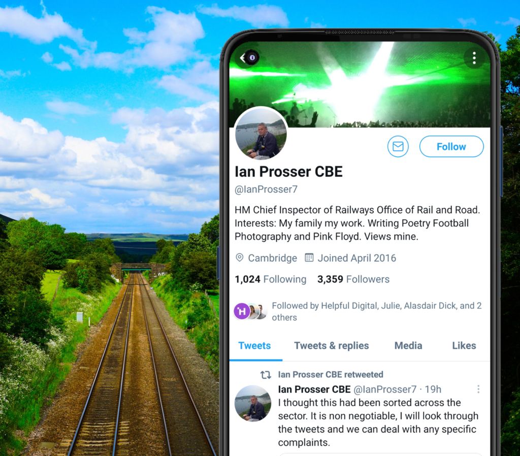 Empty railway lines with trees either side, phone on right side showing Twitter account of Ian Prosser