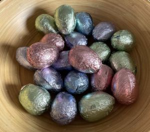 a bowl full of foil wrapped Easter eggs