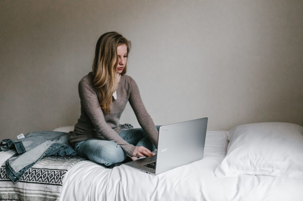 Woman using laptop on bed